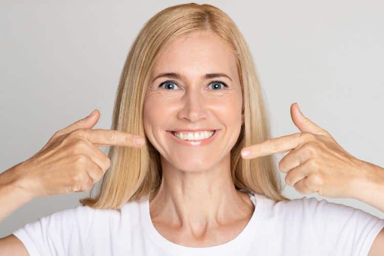 caring for dental implants woman smiling and pointing at her teeth
